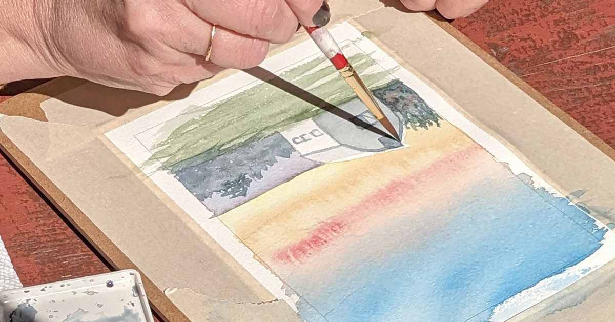 A student works on a watercolor of a landscape with a barn.